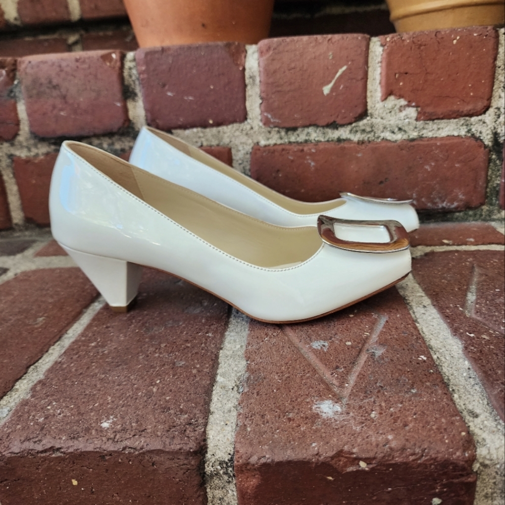 Butter low white heels with chrome toe embellishment.